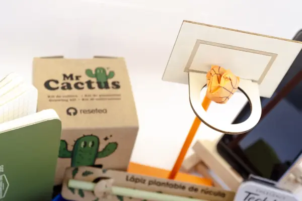 Caja regalo Musuka "Márcate un triple" que contiene: kit de cultivo de cactus, bloc de notas con canasta, set de dos bolígrafos de tinta negra, cuaderno de bolsillo, lápiz plantable, kit de reparación tecnológico, soporte para móviles con diseño de caballete