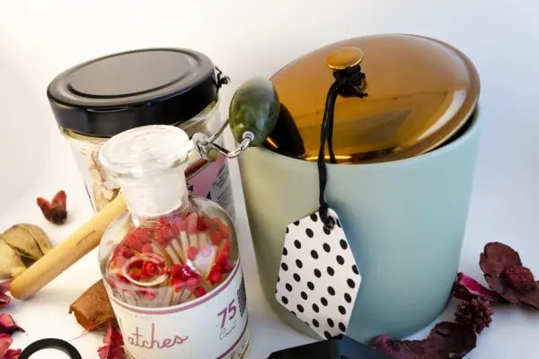Caja de regalo Musuka "Mímate" que contiene: Una vela con olor a higuera silvestre y cedro, una herramienta para velas, un tarro de sales de baño con aroma a hibisco y rosa, un rodillo de masaje facial que se convierte en bolígrafo y una botella “Paddywax” con cerillas.