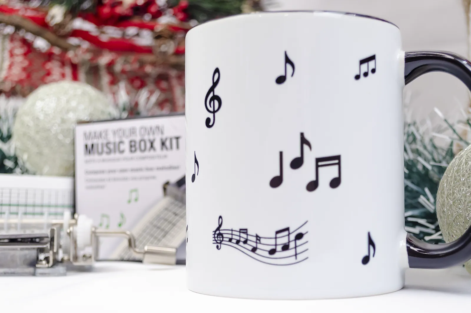 Caja regalo Musuka "Music Box" que contiene: Kit Kikkerland con una caja de música y partituras en blanco, para que puedas crear tus propias melodías. Una taza decorada con notas musicales y personalizable con el nombre que tú quieras.