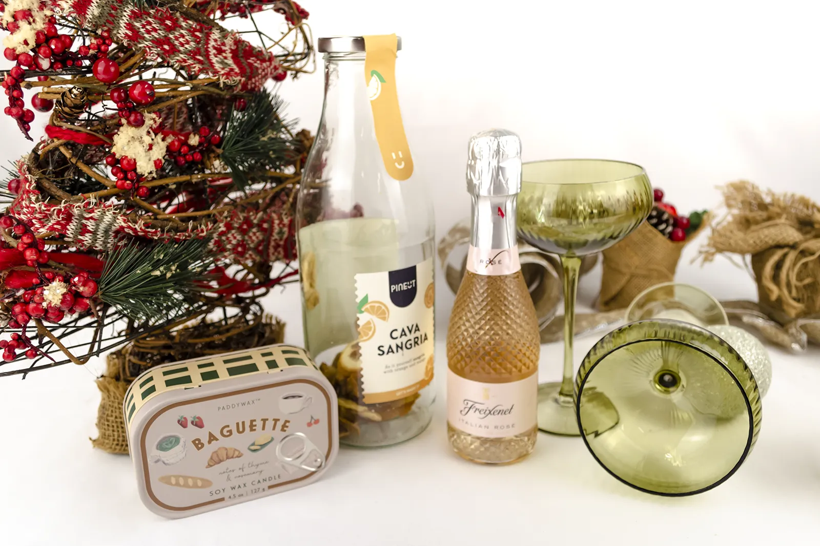 Caja Musuka “Regalo de Navidad 11" que contiene: Una botella de sangría de cava Pineut, con una mezcla de naranja y mango deshidratados. Una mini botella de vino Freixenet "Italian Rosé” de 20 cl. Una vela enlatada Paddywax “Baguette".