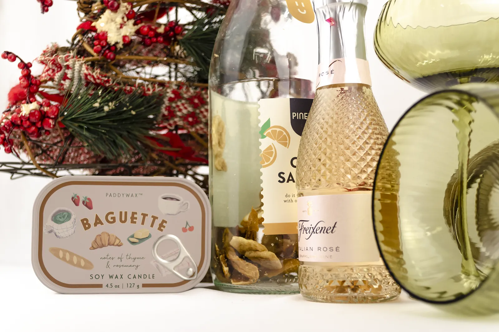 Caja Musuka “Regalo de Navidad 11" que contiene: Una botella de sangría de cava Pineut, con una mezcla de naranja y mango deshidratados. Una mini botella de vino Freixenet "Italian Rosé” de 20 cl. Una vela enlatada Paddywax “Baguette".