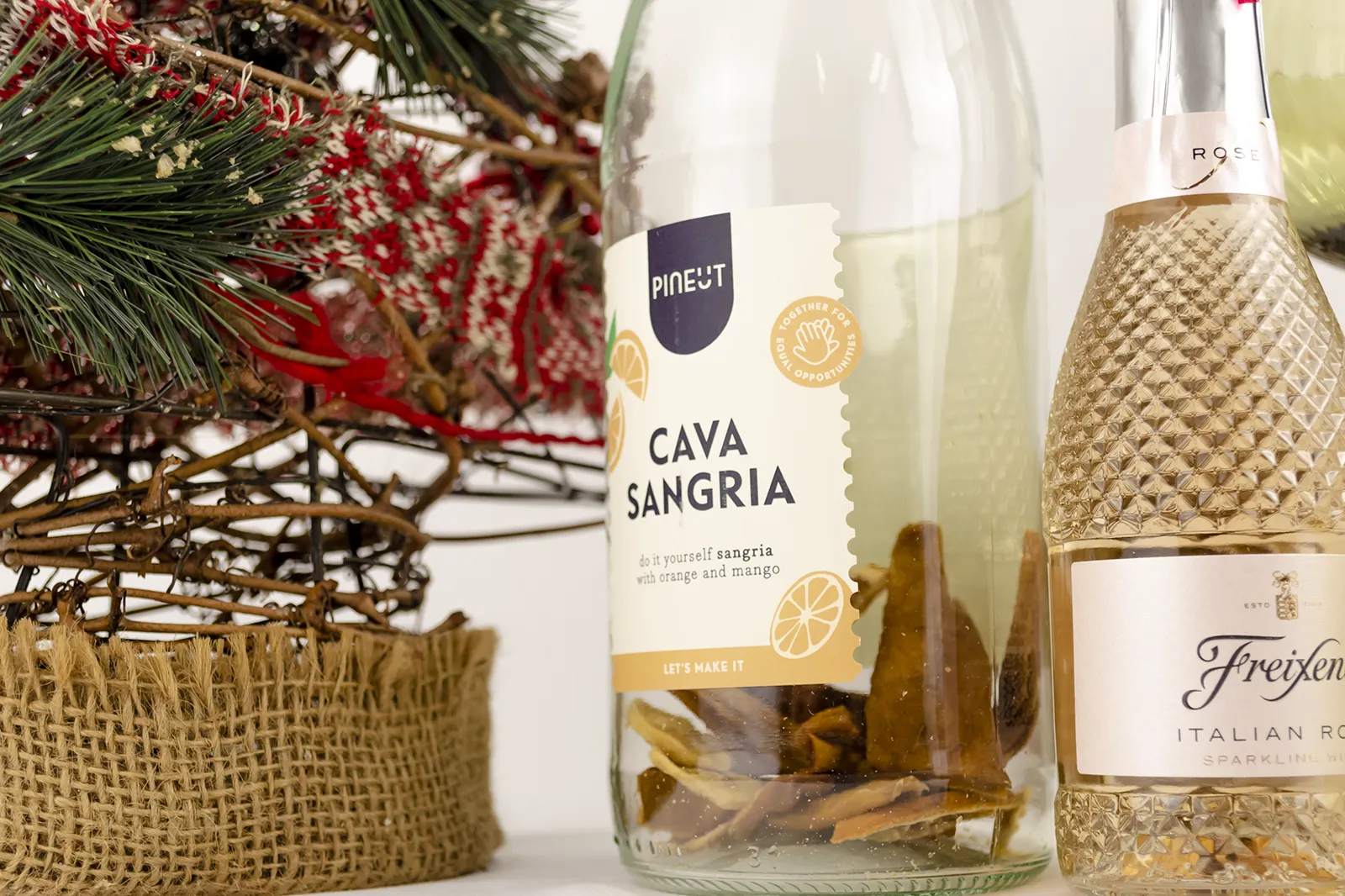 Caja Musuka “Regalo de Navidad 16" que contiene: dos copas estilo vintage “Here’s How”, de color verde. Una botella de sangría de cava Pineut. Contiene una mezcla de naranja y mango deshidratados, para preparar tu propia sangría. Una mini botella de vino Freixenet "Italian Rosé” de 20 cl.