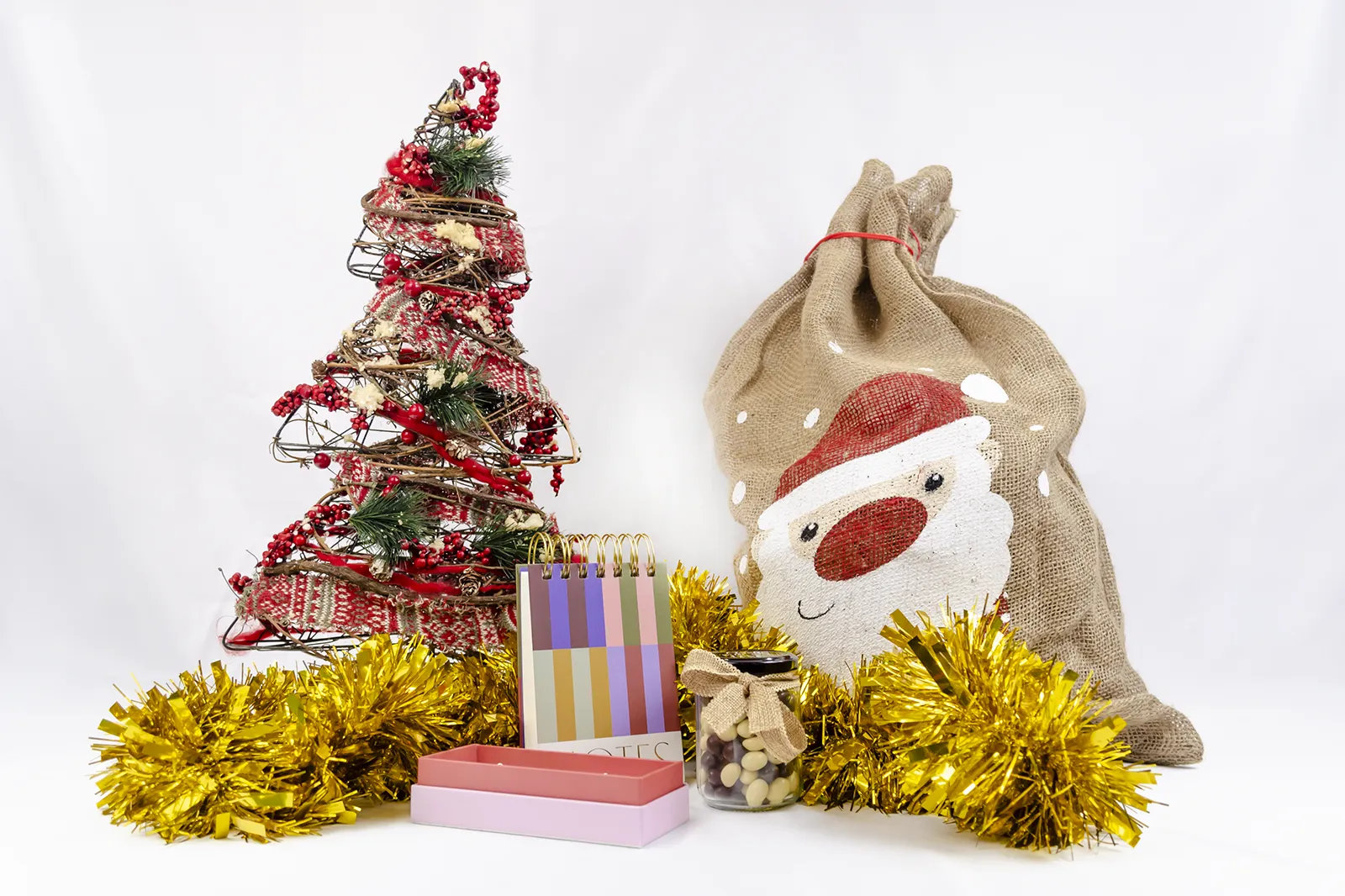 Caja Musuka “Regalo de Navidad 2" que contiene: set de bolígrafos Designworks Ink, cacahuetes cubiertos de chocolate, bloc de notas con rayas de colores.