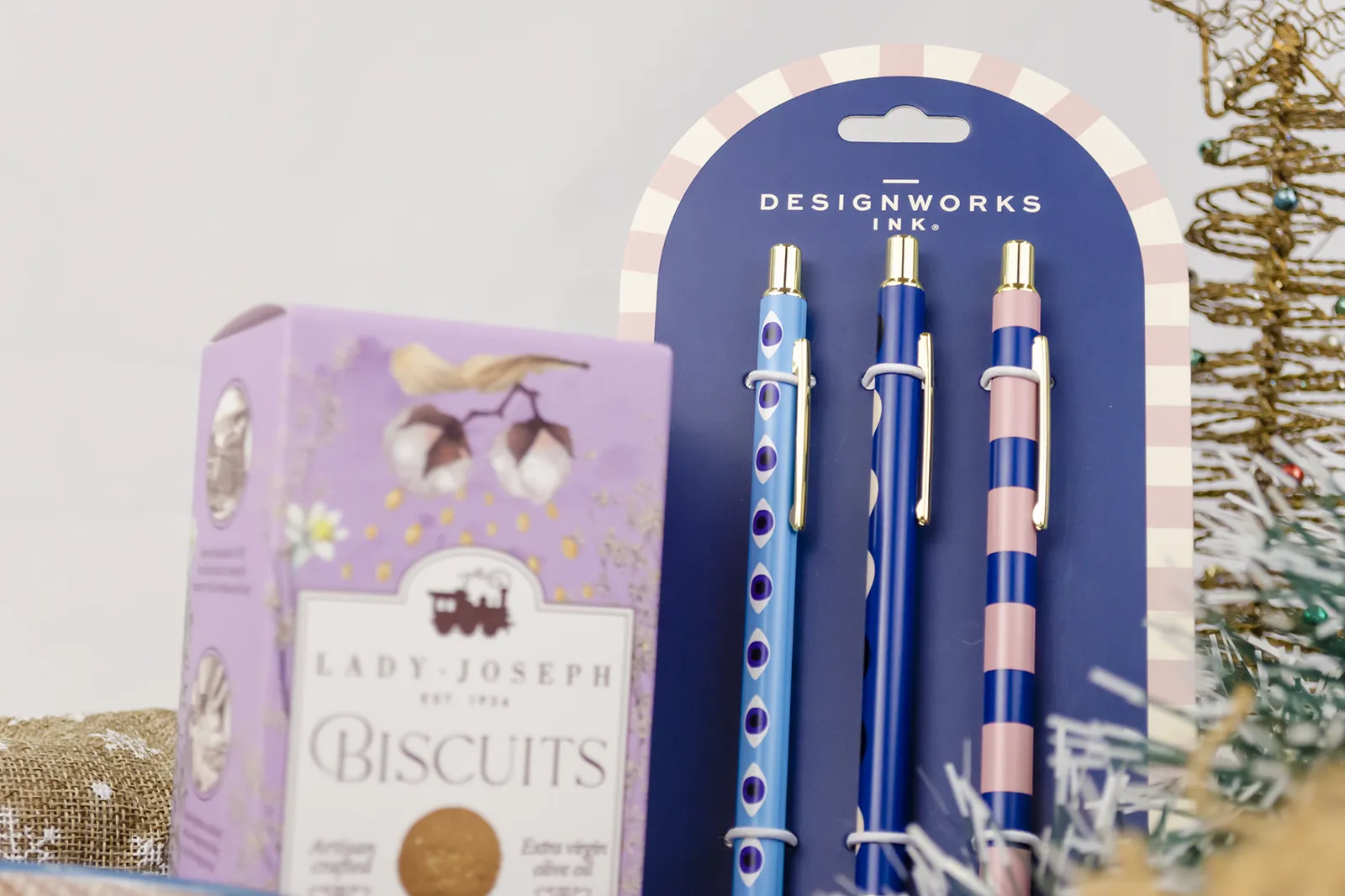 Caja Musuka “Regalo de Navidad 3" que contiene: galletas de caramelo Lady Joseph, tres bolígrafos Designworks Ink, con diferentes estampados y detalles en color dorado. Un pack de separadores de hojas Designworks Ink, de color dorado y con dibujo de una flor. Un tazón rosa de la marca Bidasoa.