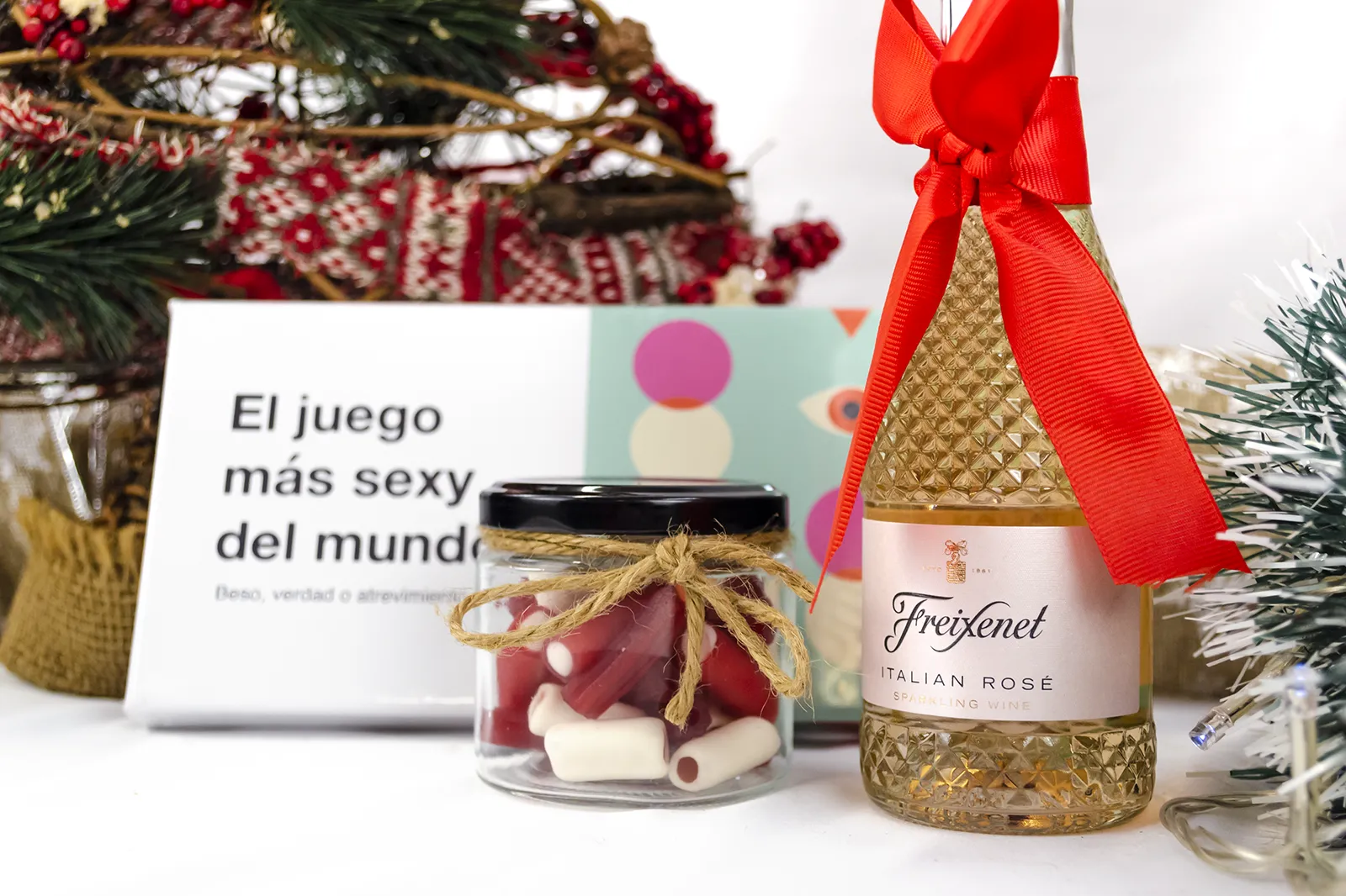 Caja Musuka “Regalo de Navidad 4" que contiene: botella de vino Freixenet "Italian Rosé”, “El juego más sexy del mundo: beso, verdad o atrevimiento”. Un tarro de cristal con deliciosas gominolas rojas.