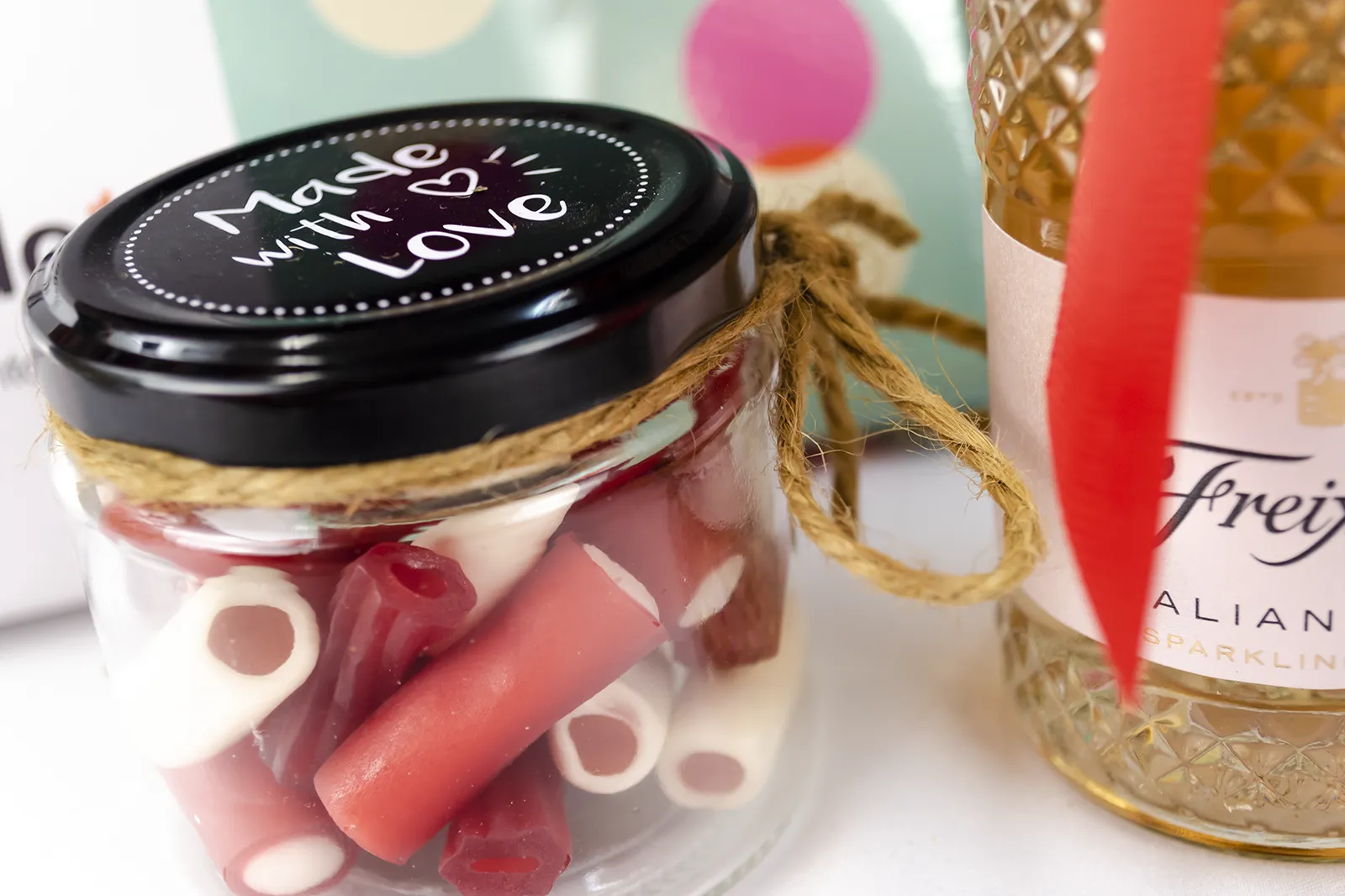 Caja Musuka “Regalo de Navidad 4" que contiene: botella de vino Freixenet "Italian Rosé”, “El juego más sexy del mundo: beso, verdad o atrevimiento”. Un tarro de cristal con deliciosas gominolas rojas.