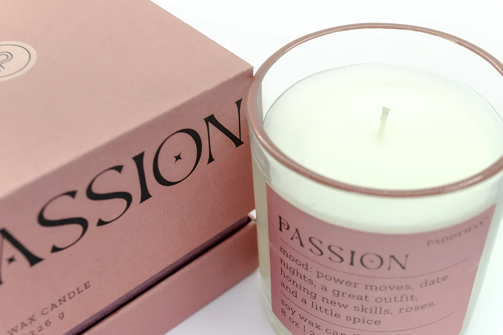 Caja Musuka “Regalo de Navidad 5" que contiene: Una vela Paddywax “Passion”, en un vaso de vidrio trasparente con borde de color rosa. Una herramienta para velas Kikkerland tres en uno.