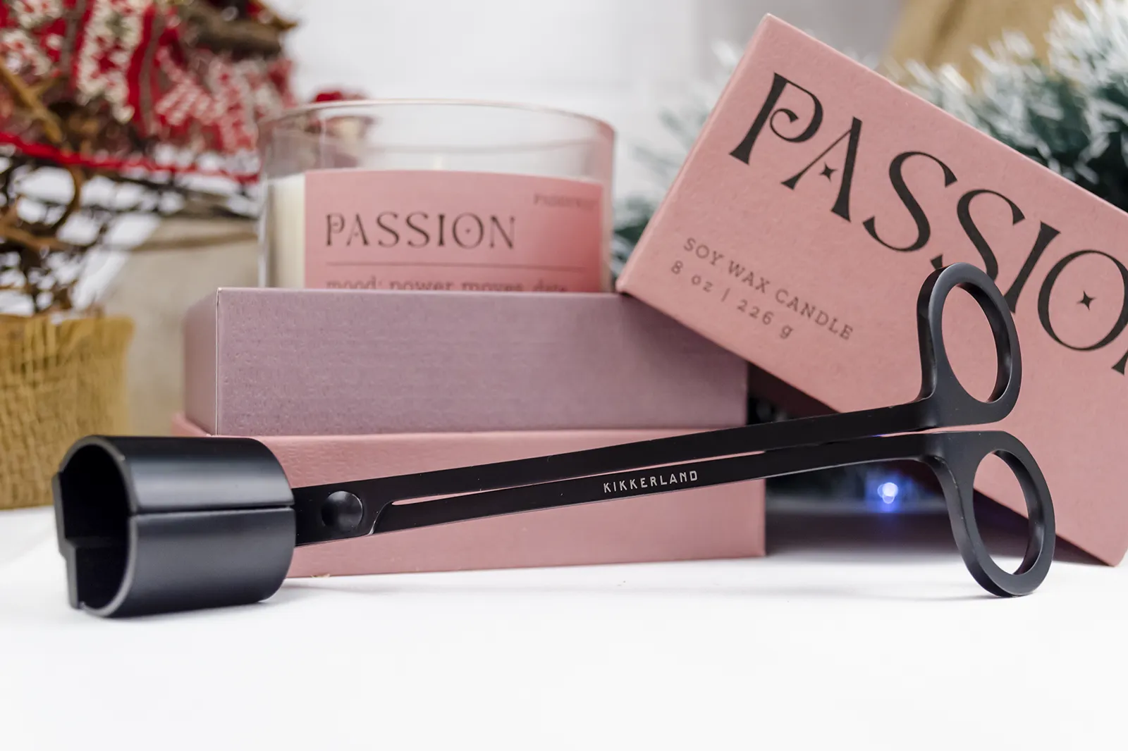 Caja Musuka “Regalo de Navidad 5" que contiene: Una vela Paddywax “Passion”, en un vaso de vidrio trasparente con borde de color rosa. Una herramienta para velas Kikkerland tres en uno.