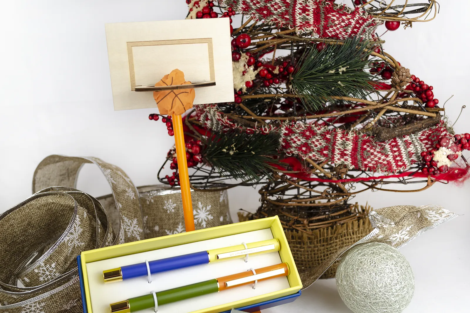 Caja Musuka “Regalo de Navidad 6" que contiene: set Kikkerland con un bloc de notas y un lápiz, con los que puedes montar una canasta. Un set de dos bolígrafos Designworks Ink, en tonos verdes y naranjas. Un cuaderno de bolsillo de tapa dura Designworks Ink con forma de pasaporte.