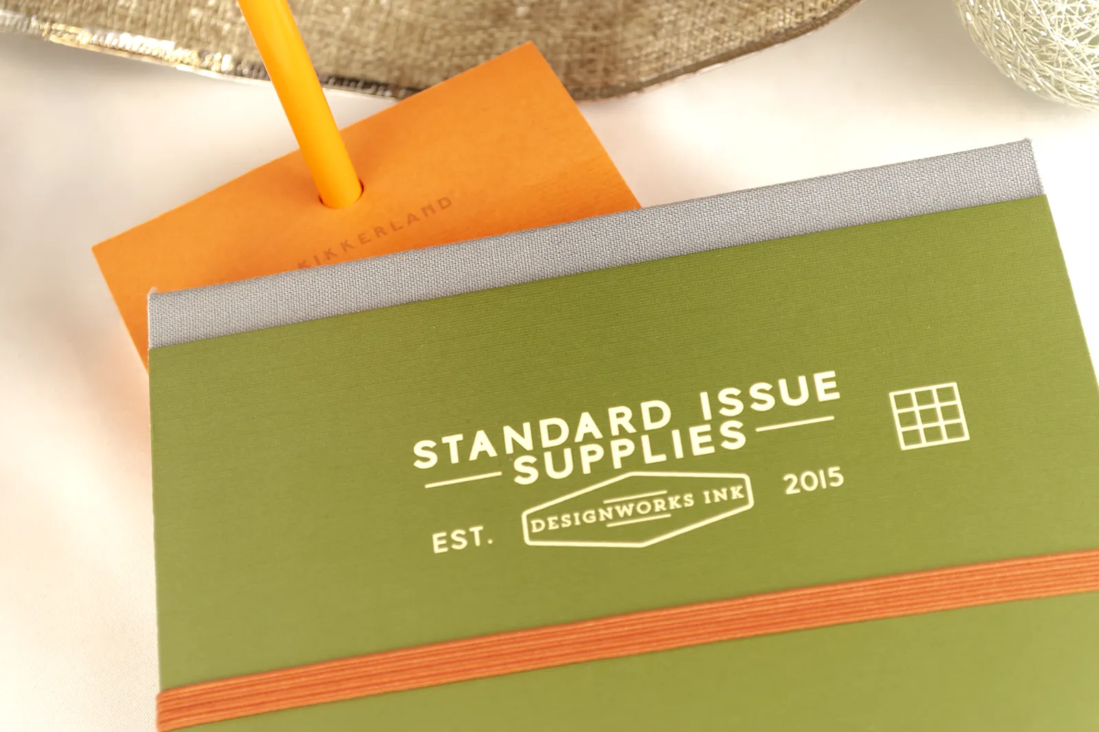 Caja Musuka “Regalo de Navidad 6" que contiene: set Kikkerland con un bloc de notas y un lápiz, con los que puedes montar una canasta. Un set de dos bolígrafos Designworks Ink, en tonos verdes y naranjas. Un cuaderno de bolsillo de tapa dura Designworks Ink con forma de pasaporte.