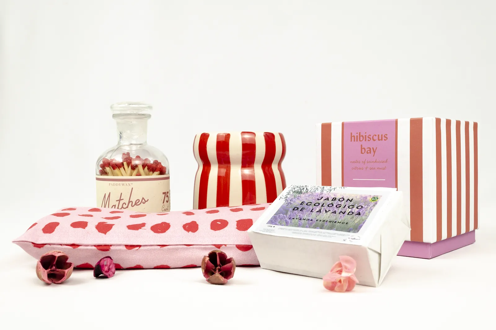 Caja de regalo spa «Aromas de La Provenza» con productos para el autocuidado, vela aromática de rayas rojas y blancas y almohada para los ojos con corazones rojos.