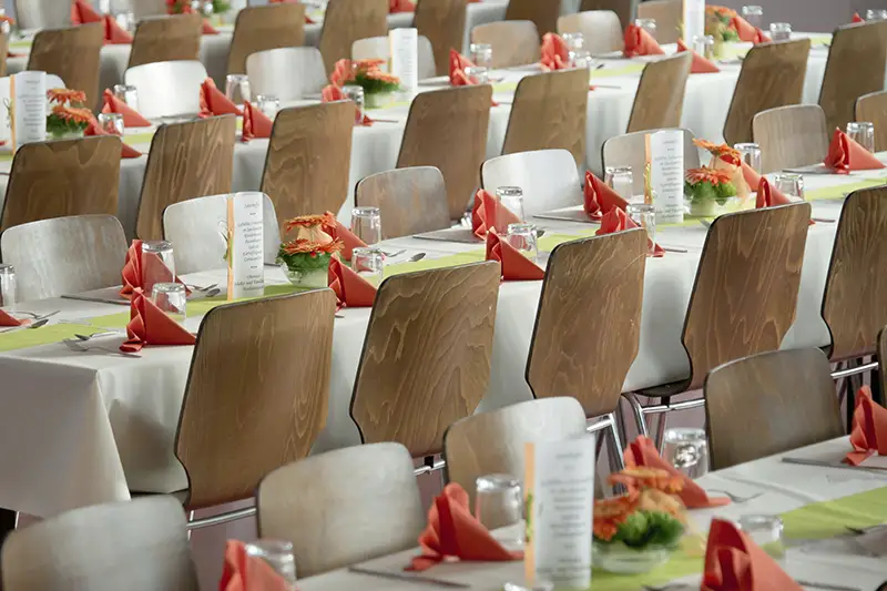 Varias mesas de comedor preparadas para la comida de un evento corporativo para empresas