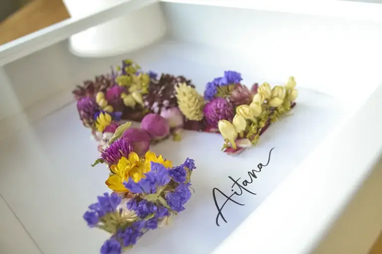 Regalo personalizado con cuadro de flores preservadas formando la inicial A y nombre Aitana