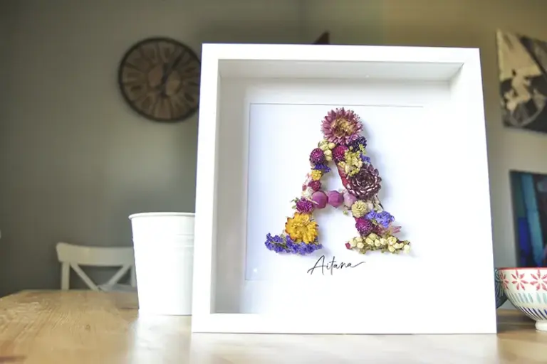 Cuadro de flores preservadas hecho a medida con inicial A y nombre Aitana sobre fondo blanco