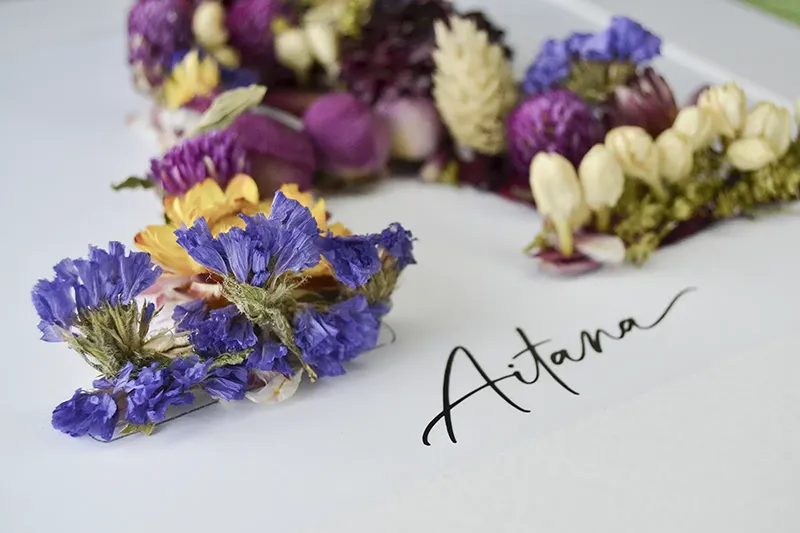 Regalo personalizado con cuadro de flores preservadas con la inicial A y nombre Aitana junto a una cesta de esparto