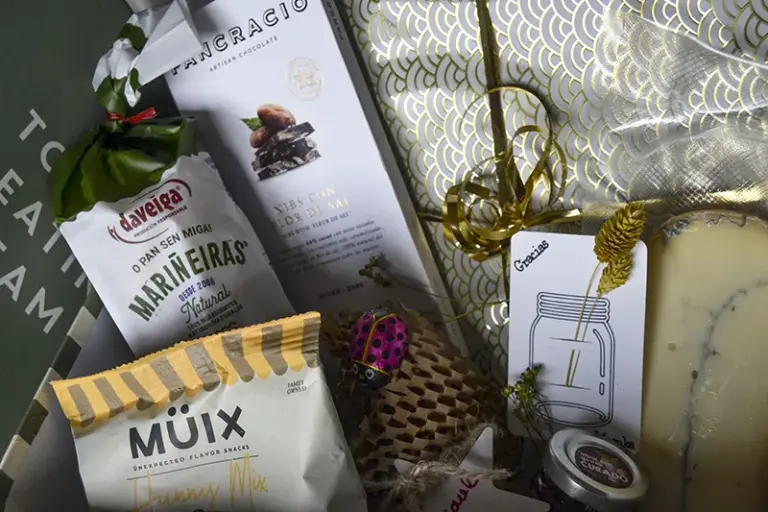 Presentación de regalo gourmet con frutos secos, galletas, chocolate artesanal, queso, mermelada y regalo envuelto