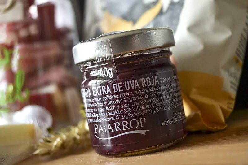 Mermelada de uva roja gourmet como protagonista de un regalo personalizado junto a frutos secos y botella de cristal