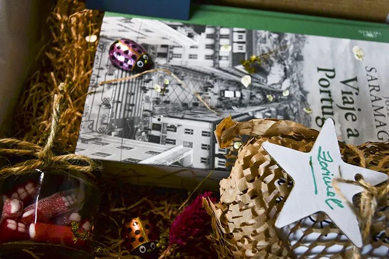 Detalle del embalaje de un regalo de cumpleaños personalizado con libro de viajes y productos presentados con cuidado