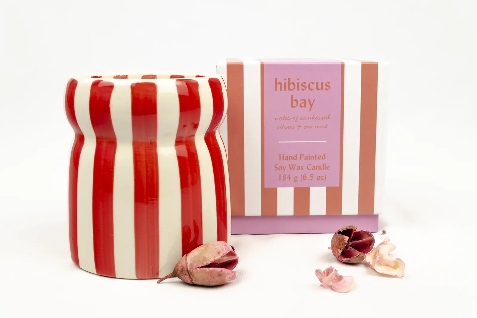 Vela aromática Hibiscus Bay de Paddywax con recipiente de rayas rojas y blancas junto a su caja, un detalle decorativo de «Aromas de La Provenza».